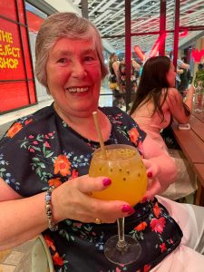 Photograph of Arthritis Action Member Gill at a restaurant with a large glass of drink.