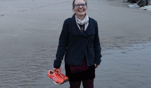 Arthritis Action Member and single mum Sophie Krank Photo on a beach, holding her orange shoes