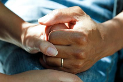 A picture of a hand holding another person's hand in support. Image used to depict a caring relationship.